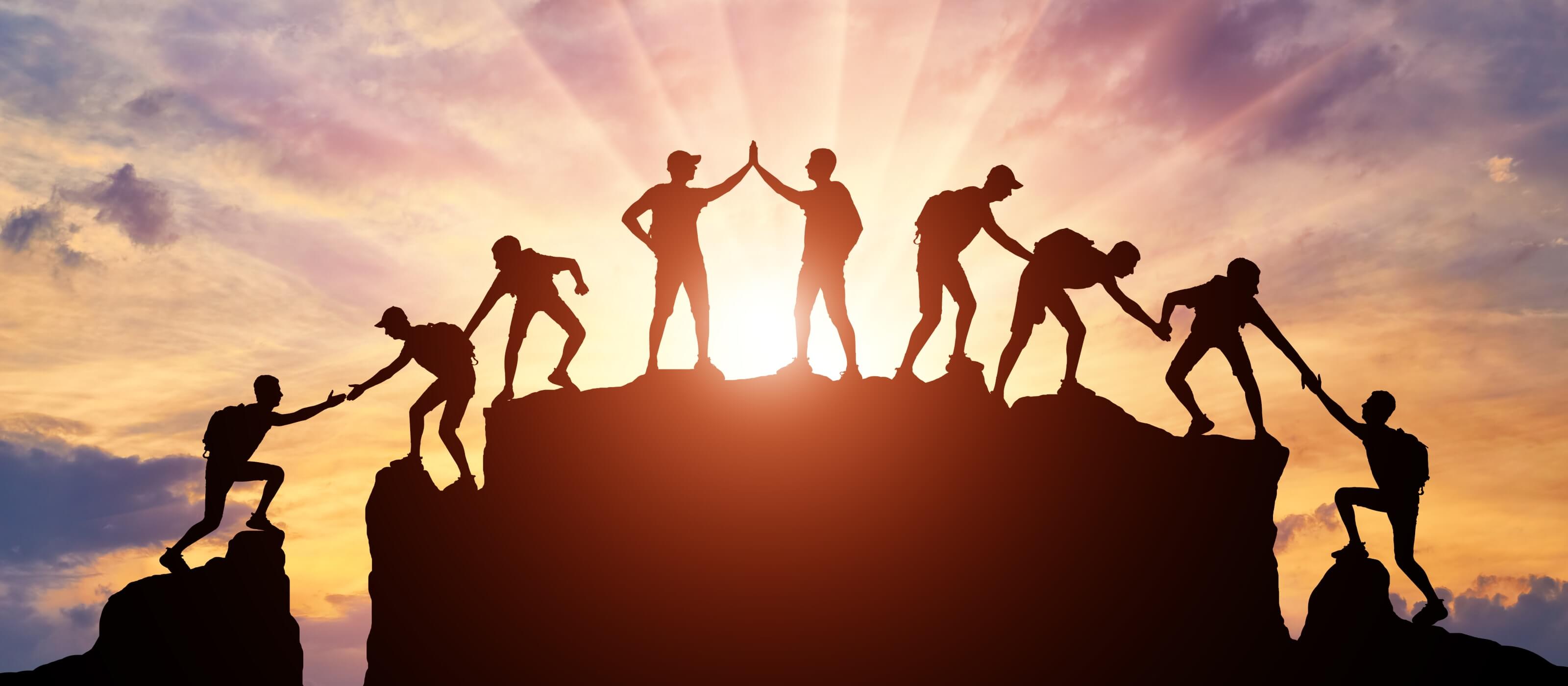 team helping each other up a mountain